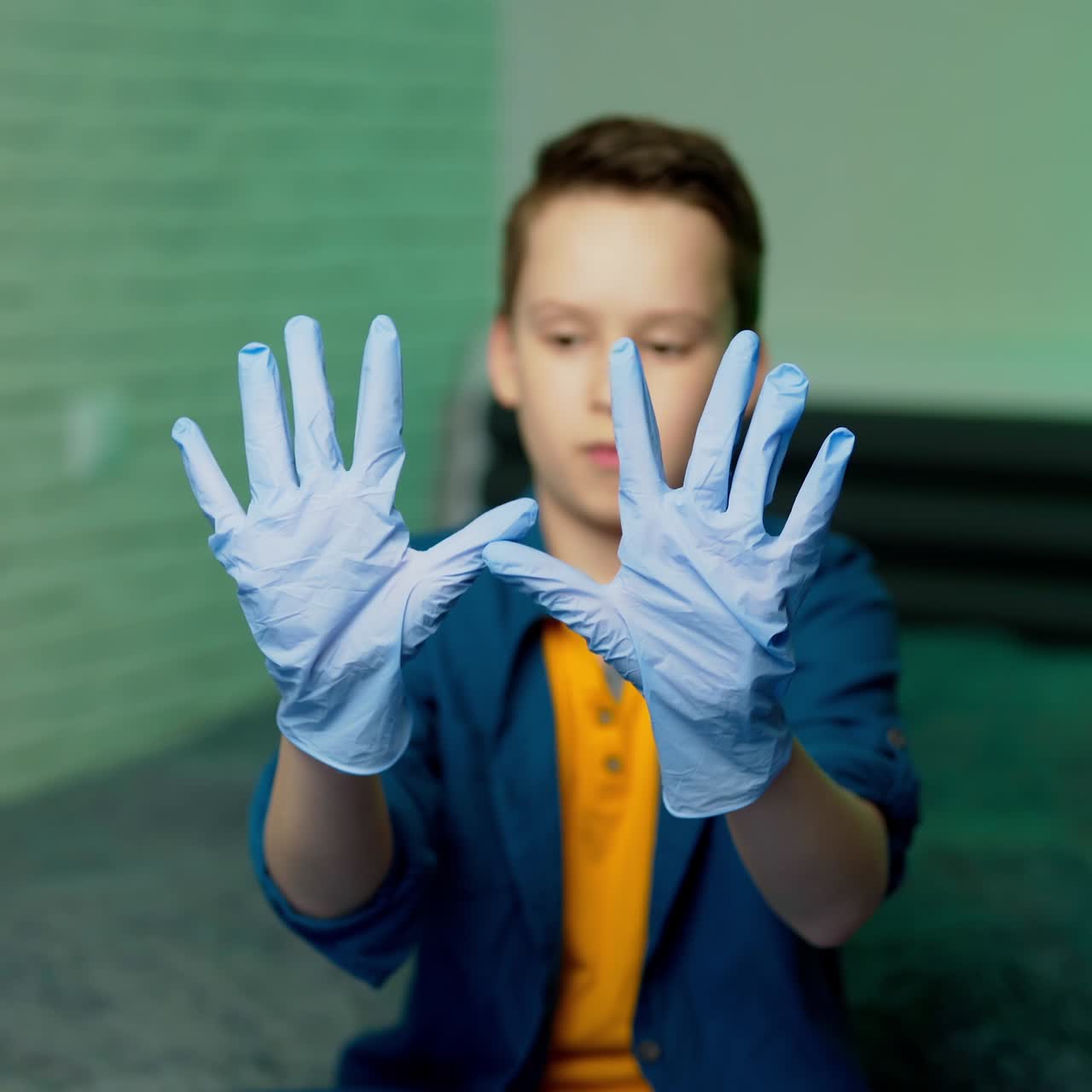 Boy wears medical rubber gloves. Boy holds hands in rubber gloves in front of camera. Stop coronavirus. Pandemic. COVID-19