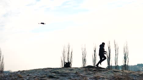 person run on rocky frozen hill while drone follow in air, bright background