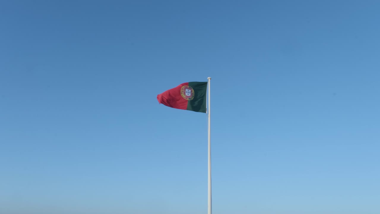 solitaria bandera portuguesa flotando en el cielo azul