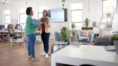 Happy-diverse-business-female-colleagues-in-discussion-using-tablet-in-office-meeting,-slow-motion