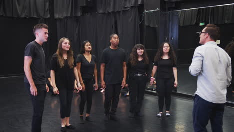 teacher with drama students at performing arts school in studio singing and dancing