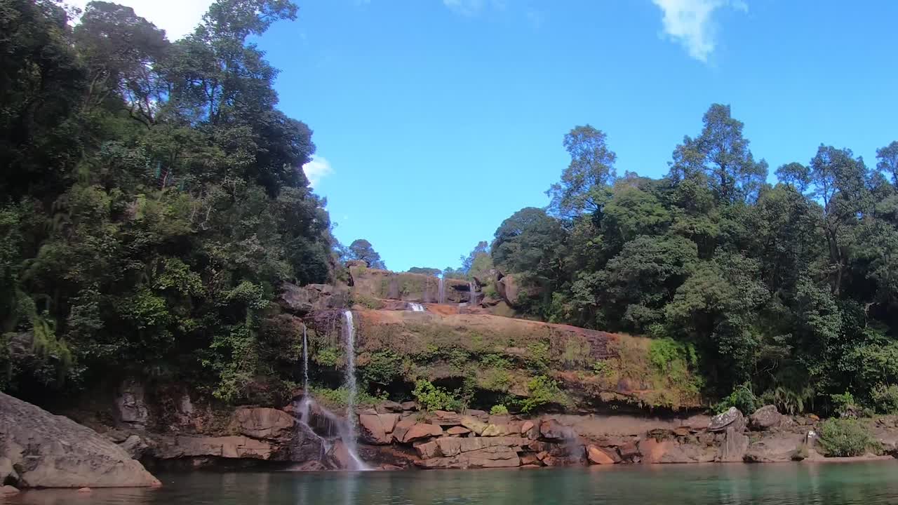 cascada natural que cae desde la cima de la montaña con un cielo azul espectacular en el lapso de tiempo de los bosques