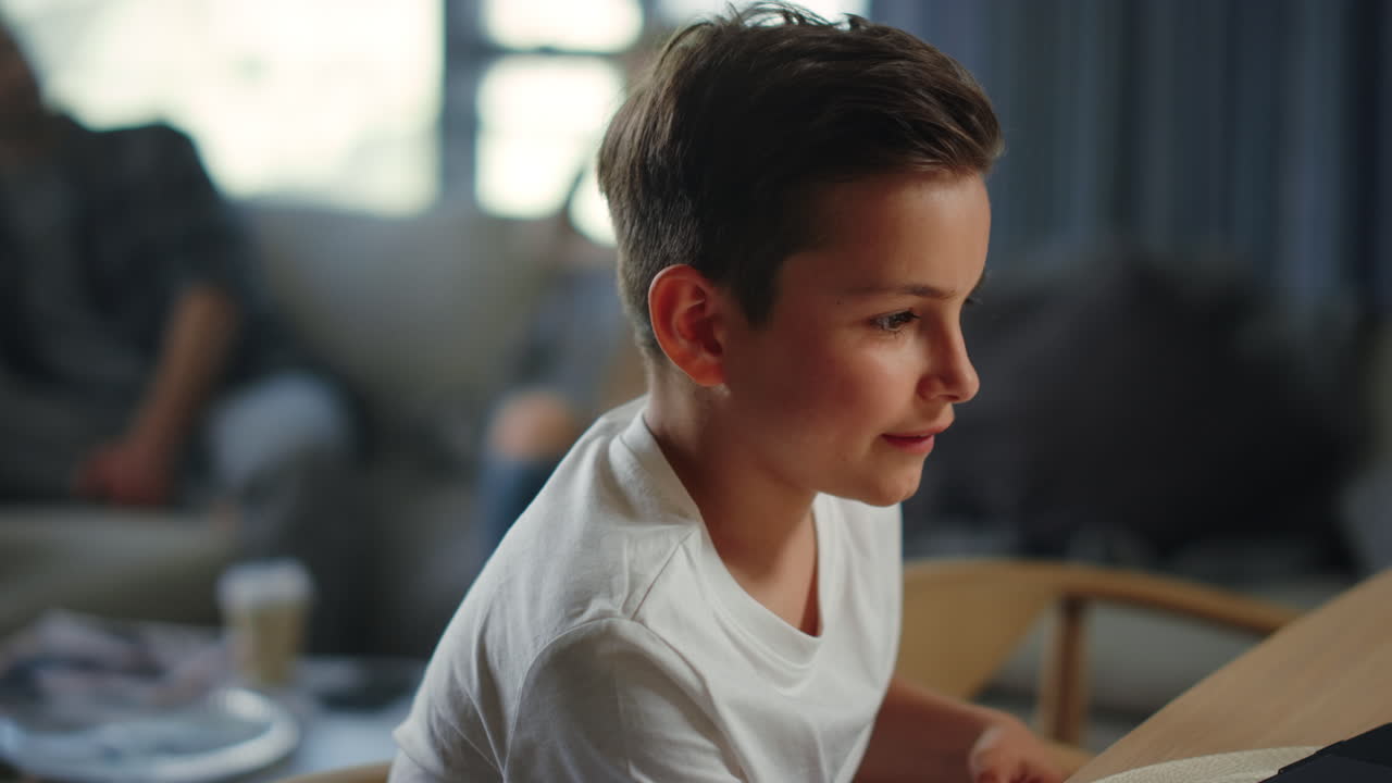 Bambino attivo che studia a casa. Ragazzo vivace che alza la mano durante una videolezione sul laptop.
