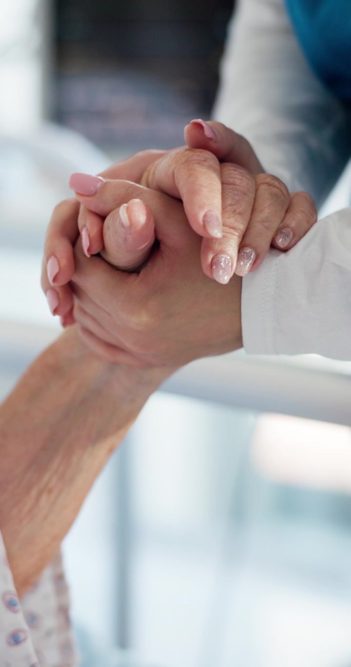 Infermiera che tiene la mano di una paziente anziana in ospedale