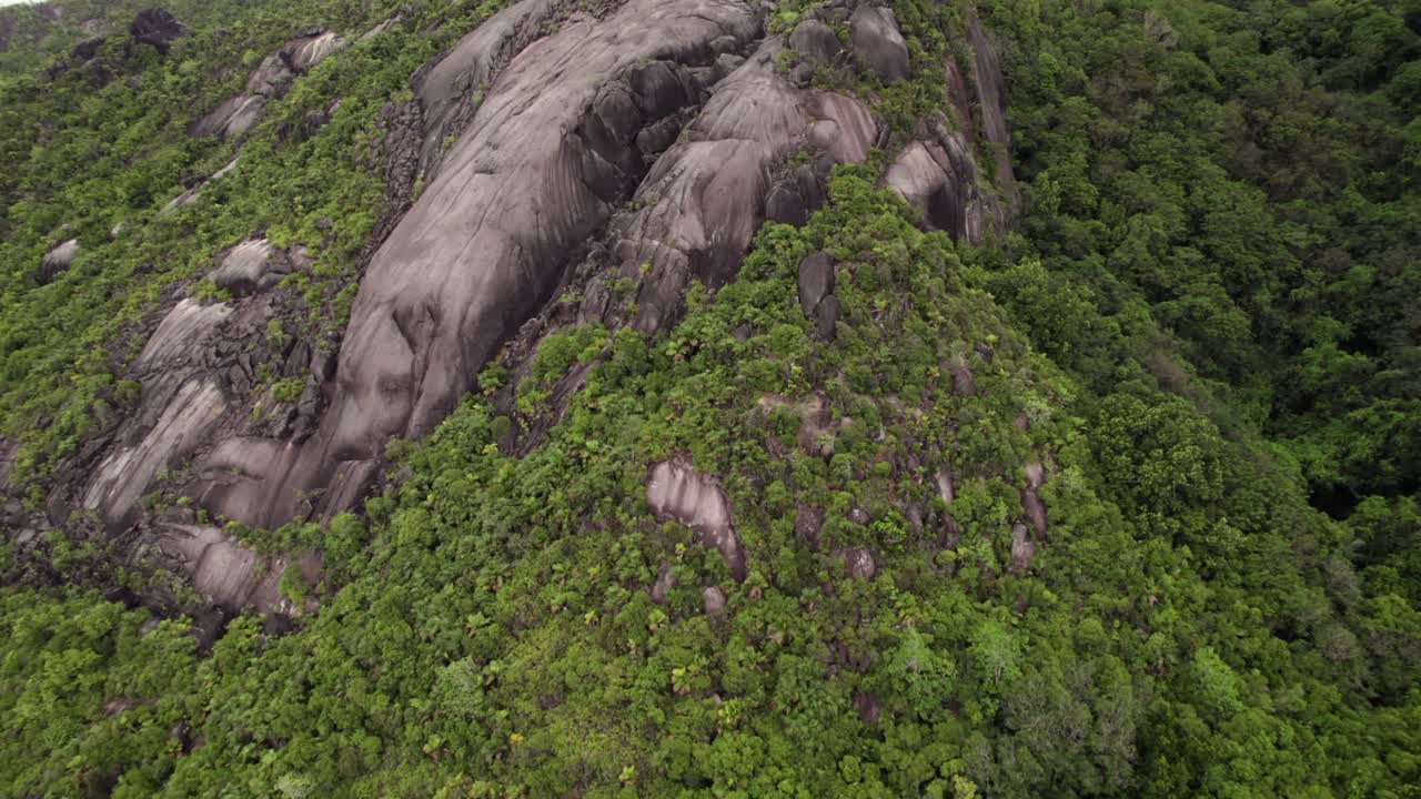 Drone footage of lush mountain with granite stones, Cap ternay, Mahe, Seychelles 30fps