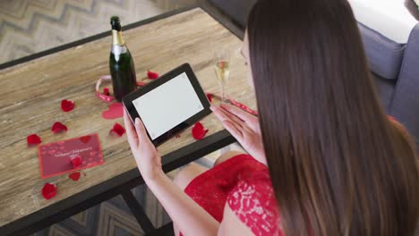 Caucasian-woman-with-champagne-making-valentine's-day-video-call-on-tablet,-copy-space-on-screen
