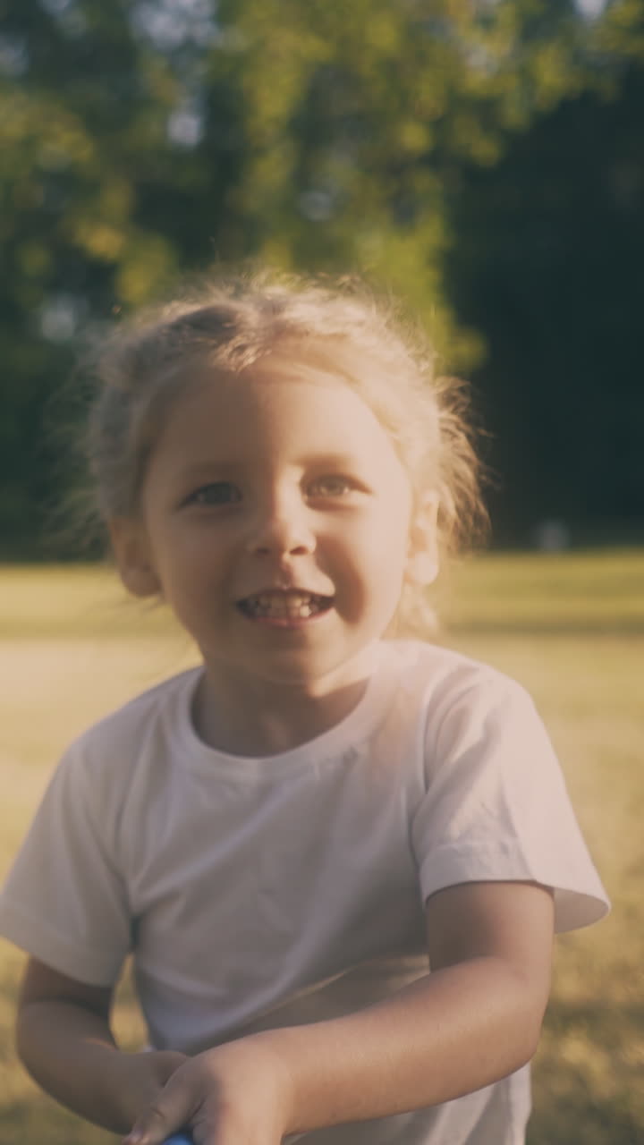 funny blonde little girl runs along park green lawn catching butterflies with net on nice sunny day