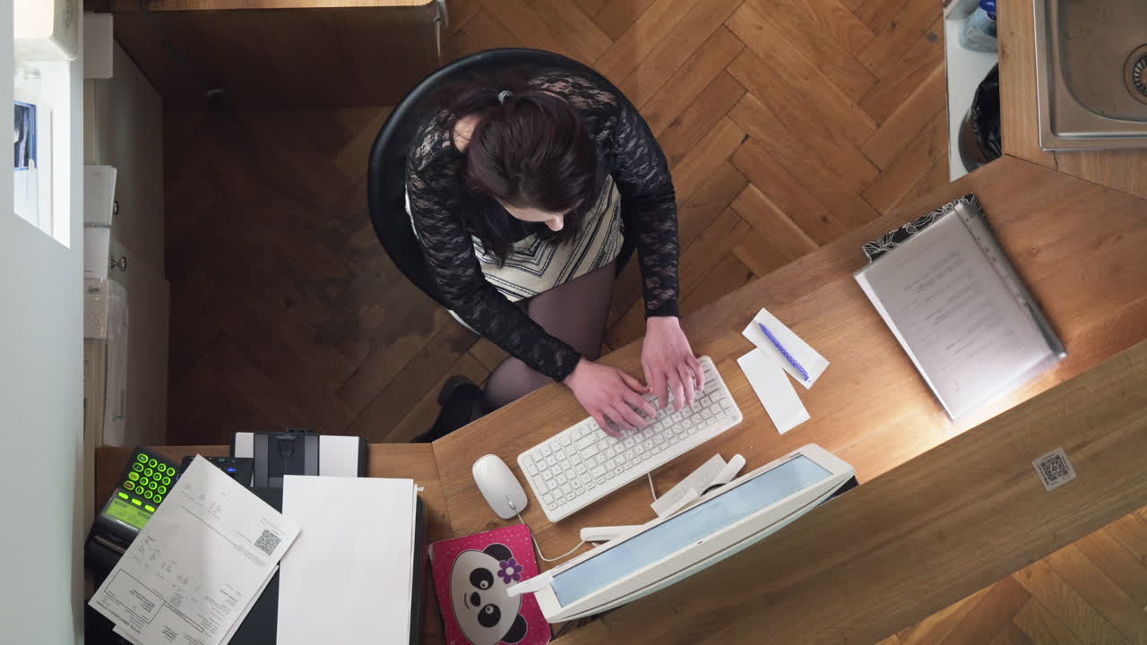 Girl using computer at reception, writing keyboard, top down closeup unique view
