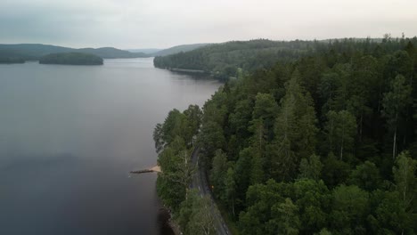 Aerial-of-lakeside-winding-forested-road,-Hällingsjö,-Sweden