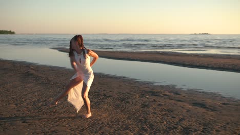 young woman in white dress dancing on beach