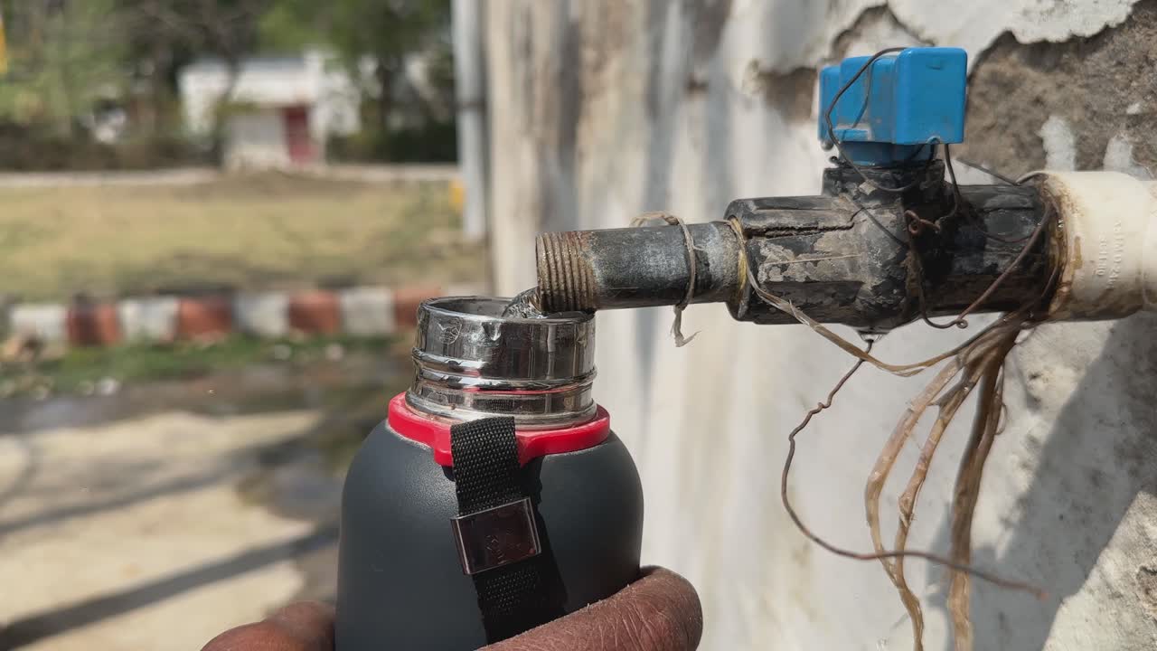 closeup of filling a water bottle from the open tap