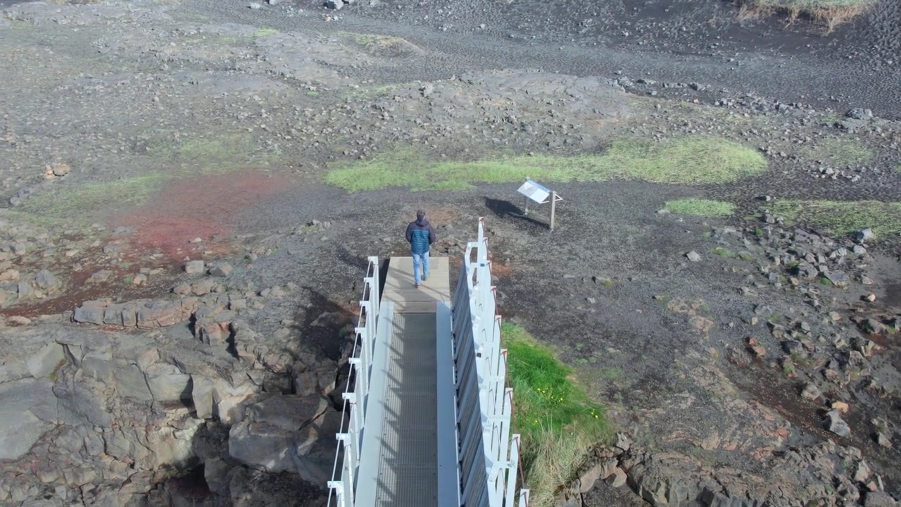 Visitor strolling along the Mid Atlantic Ridge footbridge that links the Eurasian and North American tectonic plates in the Reykjanes Peninsula, Iceland.