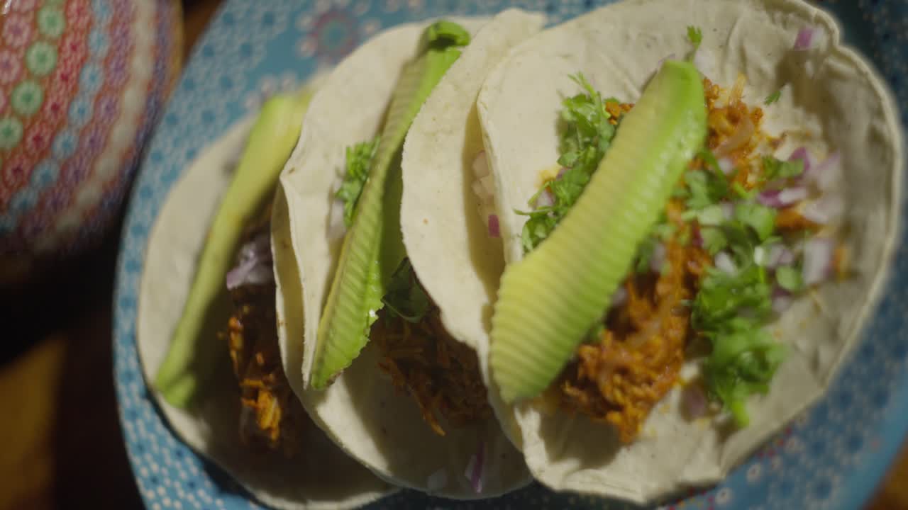 Close-up of three tacos with avocado on a plate. Mexican food concept