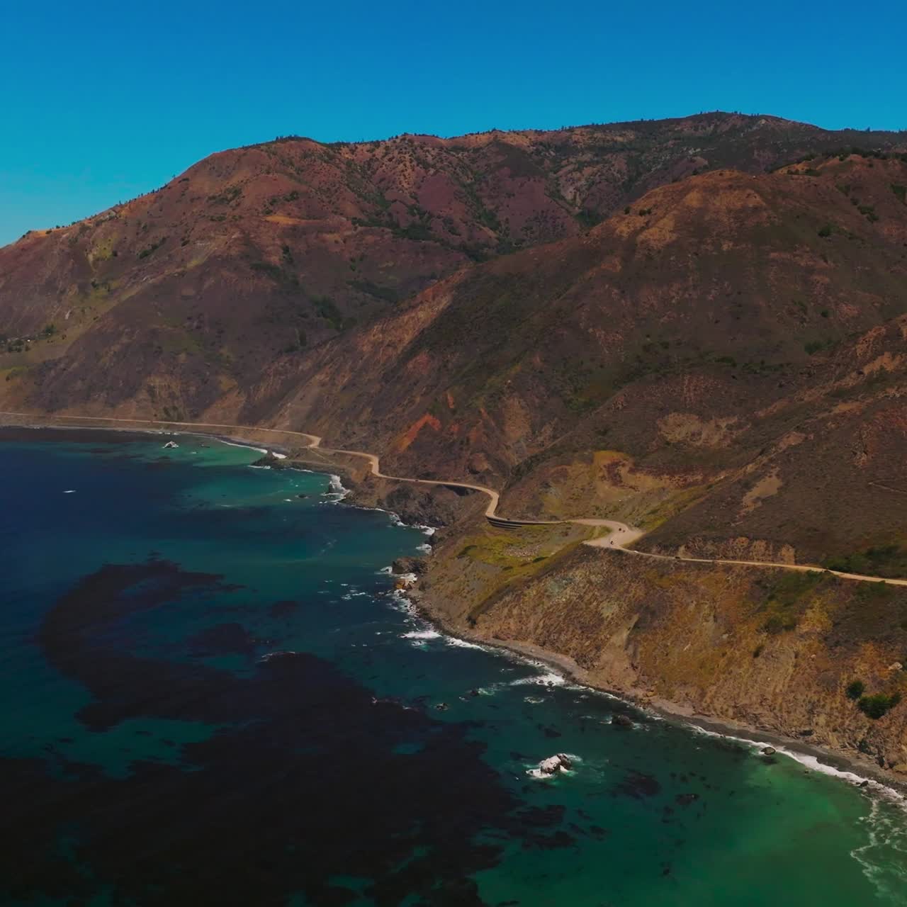 Eye-catching view of the rocks on the shore of California. Algae accumulation on the surface of sea-green water. Aerial perspective