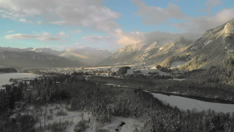 backwards aerial drone flight over a snowy landscape in the tyrol, austria. tyrolean alps covered in snow in beautiful colored clouds, the river lech and the village lechaschau are shown