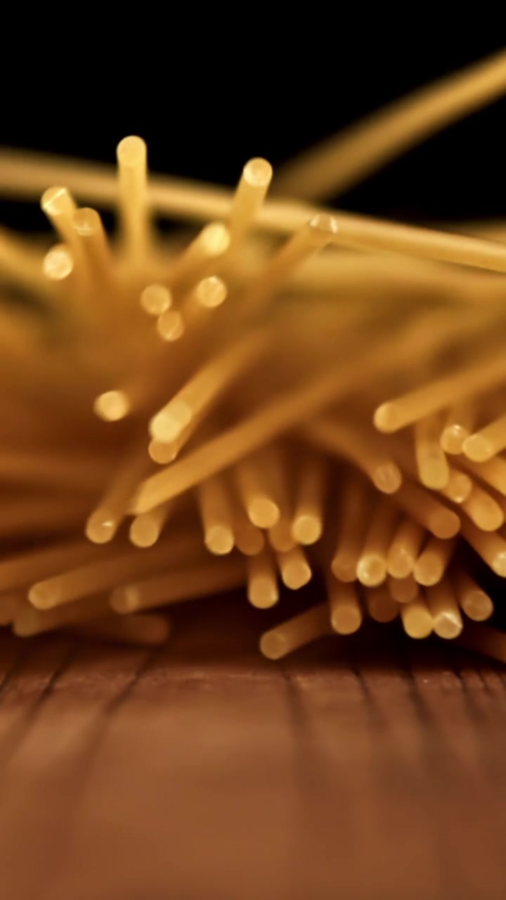 Primo piano di spaghetti secchi che cadono su una superficie di legno