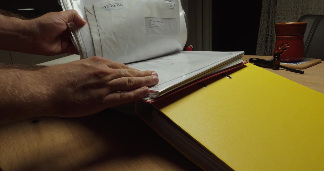 Person searching through multiple binders for a specific document. Ideal for paperwork, document search, office stress and administration.