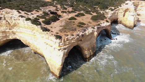 4k aerial drone footage circling a unique rock formation found along the shoreline near the coastal village of benagil, portugal