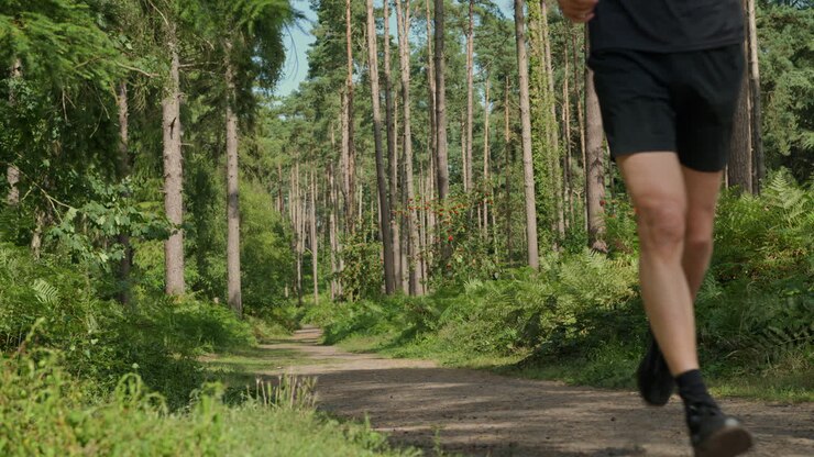 Mid Adult Couple Exercising Doing Work Out Outdoors Running Along Track Through Forest Towards Camera Wearing Sports Clothing Shot In Real Time