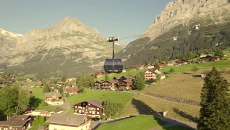 dolly de lado de izquierda a derecha siguiendo una cabina ascendente del sistema de coches tricable eiger express en grindelwald en una fantástica luz vespertina con cielo despejado