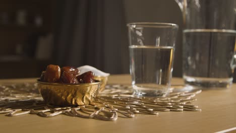 bowl of dates with glass of water on table in muslim home celebrating eid 2