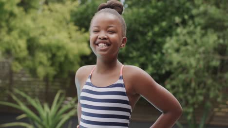 retrato de una feliz chica afroamericana con traje de baño en el jardín en cámara lenta