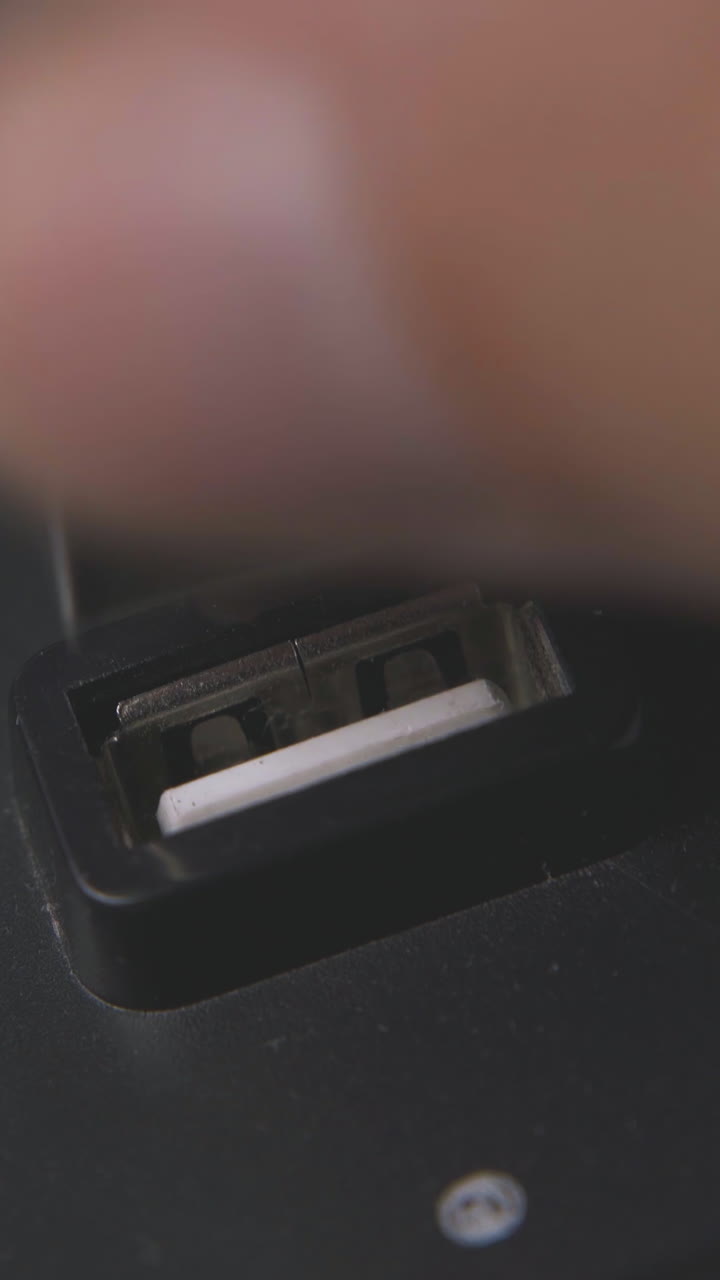 person takes off usb cable from black hub and presses button against white surface extreme close view