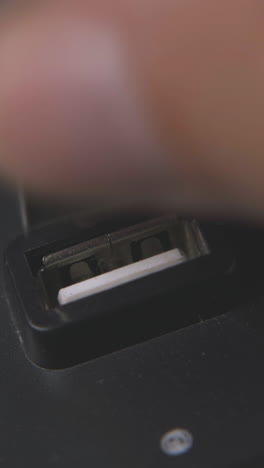 person takes off usb cable from black hub and presses button against white surface extreme close view