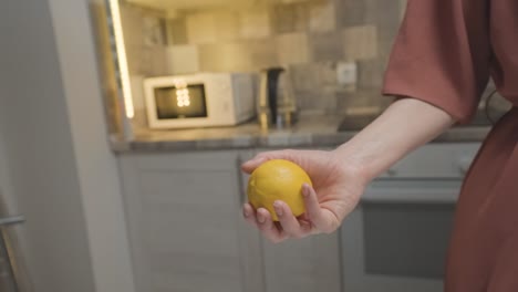 woman holding a lemon in a kitchen