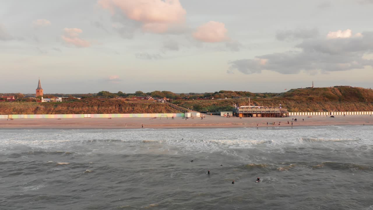 Surfere foran turistbyen Domburg i Holland under solnedgang.