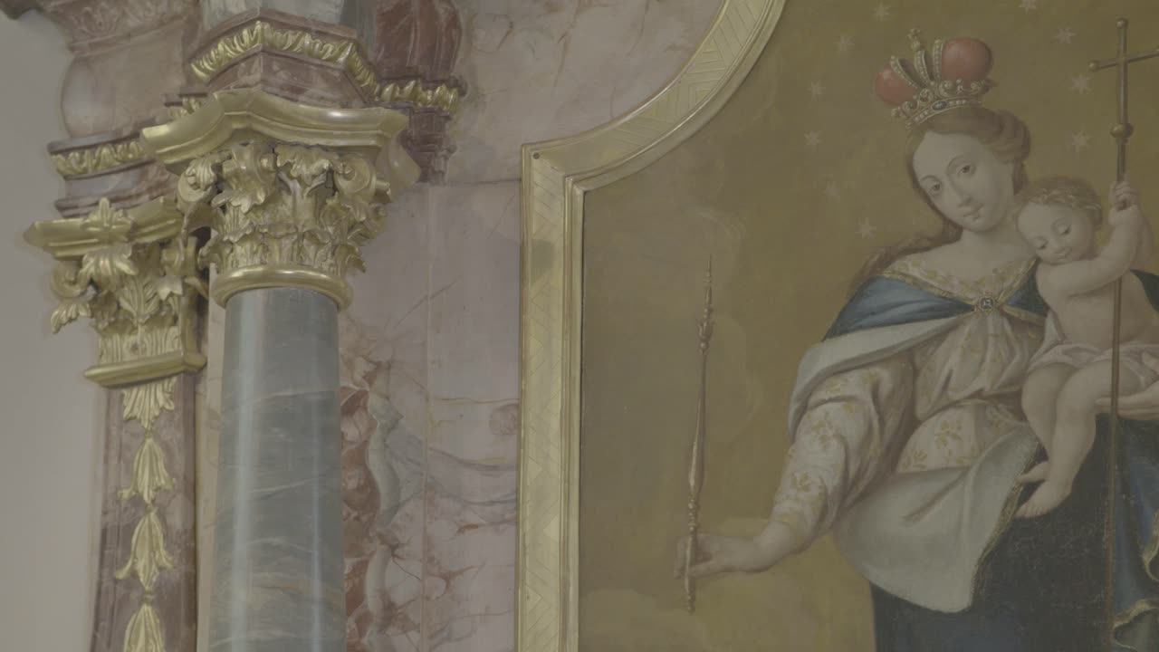 카메라는 바로크 제단의 그림 위에 예수를 팔에 안고 있는 성모 마리아를 향해 이동합니다.