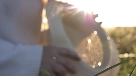 Defocused-shot-of-woman-holding-straw-hat-in-the-sunshine-medium-abstract-shot