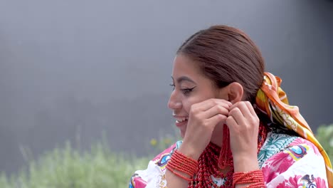 cinematic clip of a young brunette latin girl wearing the traditional outfit named cayambeñas putting on her earings and smiling