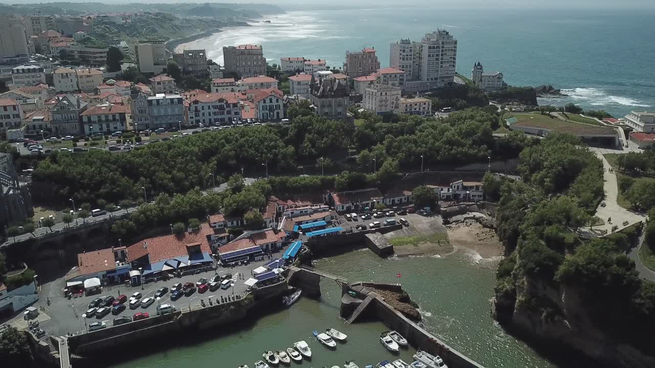 Port des Pêcheurs, Fishermen's Port in Biarritz, moored boats, traditional houses, and city in background, French Basque Country, France. Aerial drone rising