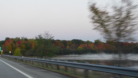 stunning shot from moving vehicle of marvelous foggy lake surrounded with trees