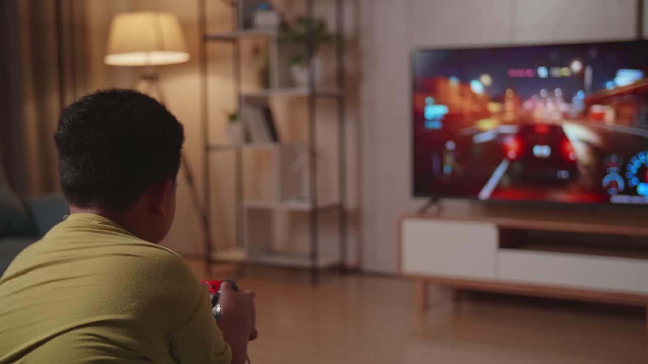 Bambino gamer che gioca a un gioco di corse automobilistiche in TV a casa.