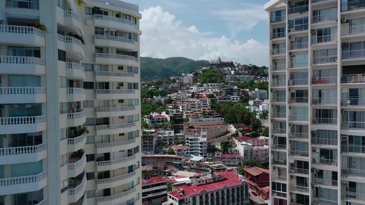 Ripresa aerea grandangolare con drone a movimento verticale della città di Acapulco, Messico, di giorno.