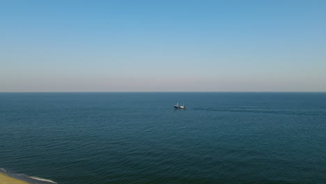 Lonely-cutter-sailing-on-calm-Baltic-sea-close-to-shore,-clear-sky-and-low-waves,-aerial-Hel,-Poland