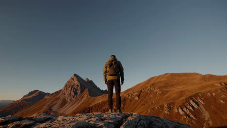 hiker looking out over a vast mountain landscape at sunrise or sunset