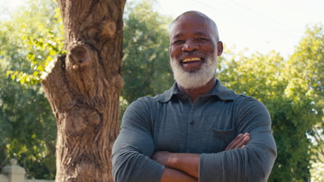 portrait of smiling senior man standing outdoors in garden park or countryside