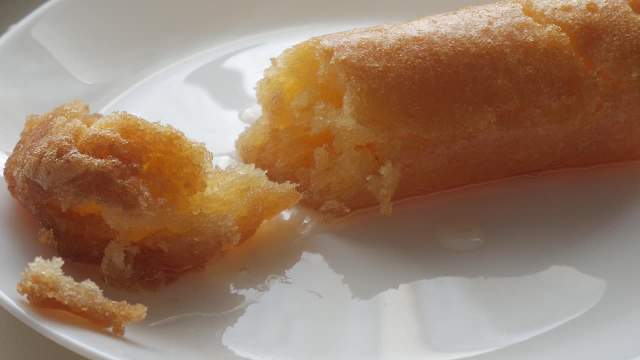 Golden fried Chachepo split open on white plate, soaked in syrup, soft and moist