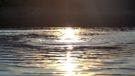 Imágenes-En-Cámara-Lenta-De-Salpicaduras-En-La-Superficie-Del-Agua-Contra-Un-Fondo-De-Luz-Del-Atardecer