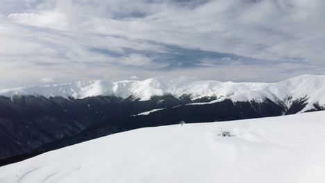 Expansive-snow-covered-Iezer-Papusa-mountains-under-blue-skies,-Gainatu-Refuge-visible