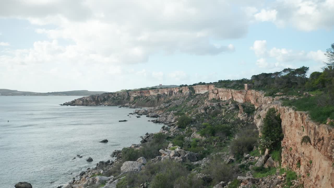 AERIAL: Steep Coastline in Mellieha Bay with Sharp Limestone Rocks at the Bottom of Shore