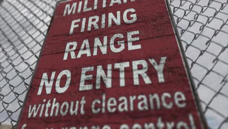 high quality 3d cgi render with a close up orbiting shot of a chainlink fence at a high security installation in a desert scene, with a military firing range no entry sign