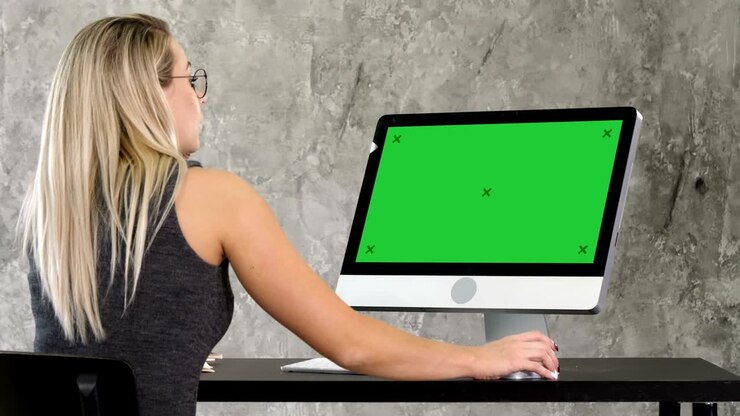 Giovane operatrice amichevole che parla e lavora al computer. Display mock-up su Green Screen