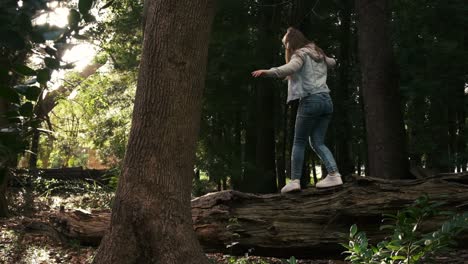 young girl balancing skill on large fallen tree trunk in woodland wilderness