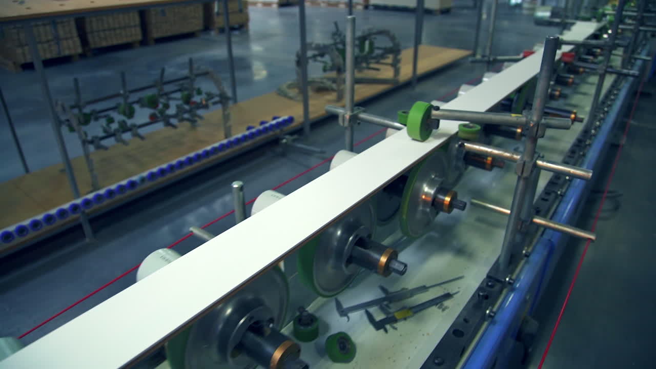 Modern equipment at factory manufacturing doors. Walking along the conveyor belt with numerous rollers rotating.