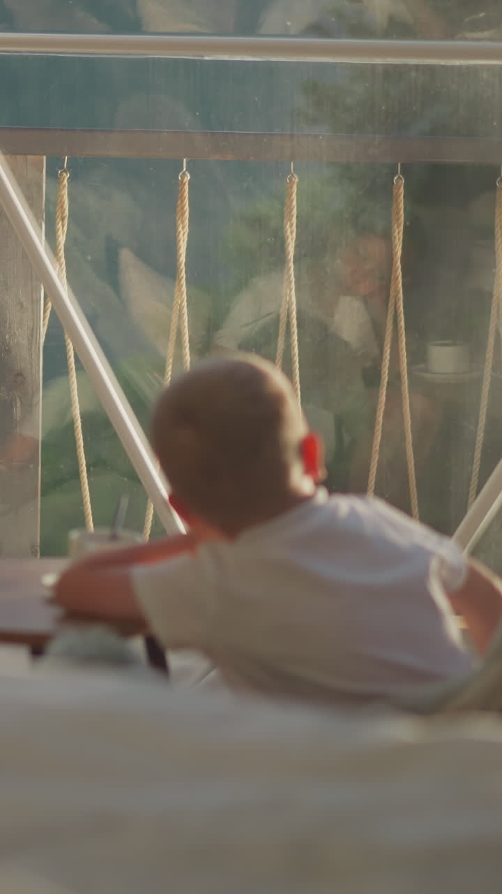 Children observe nature outside glamping tent. Calm siblings sit at table at beginning of new day on summer vacation. Bored kids in hotel dome