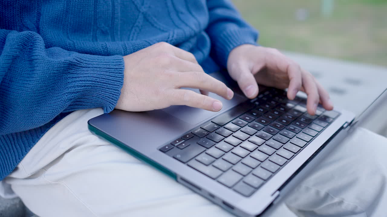 Programmer writing code outdoors on laptop